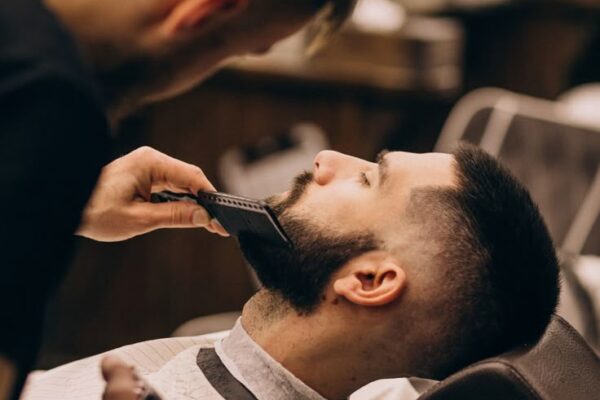 Homem num salão de barbearia a cortar o cabelo e a barba _ Foto Grátis